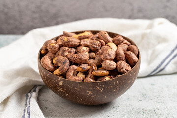 Roasted cashews on a gray background. Cashews in a coconut bowl. close up