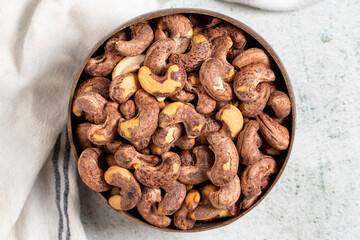 Roasted cashews on a gray background. Cashews in a coconut bowl. Top view