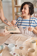 Woman with apron enjoying while having a pottery class. Craft, art and hobbies concept.