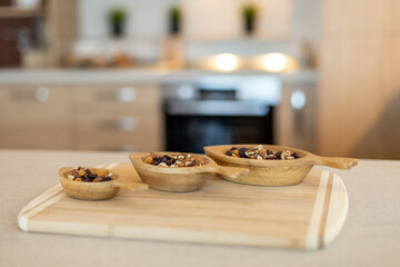 Mixed nuts and raisins in wooden bowls in the kitchen