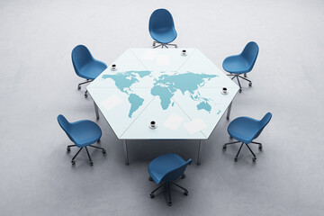 Top view of hexagonal conference table with map and coffee cup, chairs on concrete floor. Meeting...
