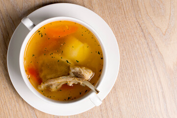 soup made from lamb ribs with potatoes and carrots in a white plate on wooden background
