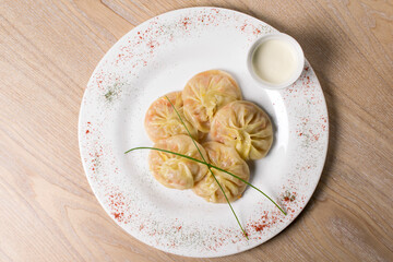 Manti with meat and sauce on a white plate