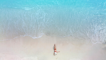 Above view with woman body in bikini sunbathing as laying on the  beach, blue sea water in...