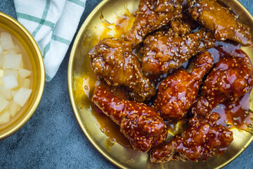 Korean style fried chicken with plain and spicy flavor suitable for meals and snacks served on golden dish.