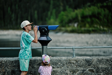 Boy look at panoramic telescope overlooking in Vorderer Gosausee, Gosau, Upper Austria.