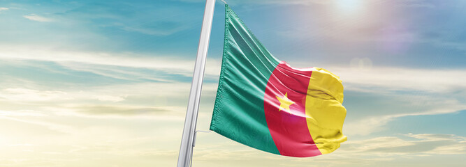 Waving Flag of Cameroon in Blue Sky. The symbol of the state on wavy cotton fabric.
