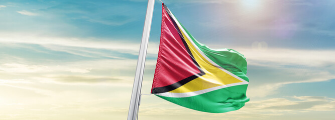 Waving Flag of Guyana in Blue Sky. The symbol of the state on wavy cotton fabric.
