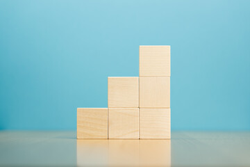 Pyramid of empty wooden blocks on table blue background.
