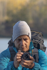 Obraz premium Portrait of traveler man at lake in autumn taking a photo with the digital camera