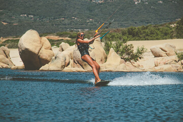 Woman kite-surfing standing on her kite-surf board on the sea with the Corsican mountains in the background near Propriano