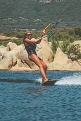 Woman kite-surfing standing on her kite-surf board on the sea with the Corsican mountains in the background near Propriano