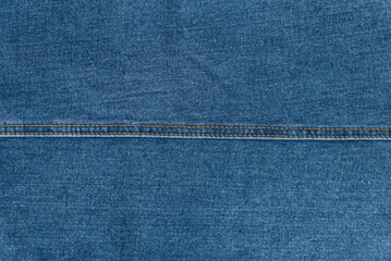 Jean fabric with brown stitching seam in middle. Texture blue denim background