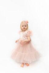 Little barefoot girl wears pink dress with satin skirt. Happy princess in festive outfit on white background. Vertical frame