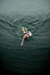 Athlete in swimming costume swimming the crawl in a mountain lake in the Pyrenees, seen from above