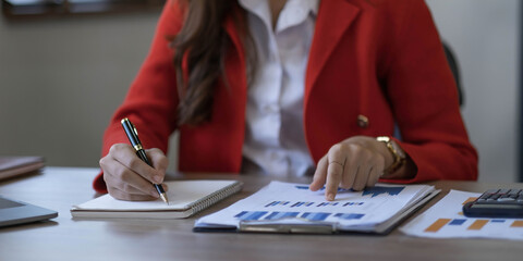 Asian Business woman using calculator and laptop for doing math finance on an office desk, tax, report, accounting, statistics, and analytical research concept