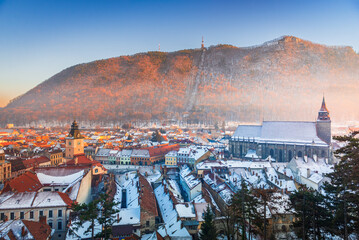 Brasov, Romania. Black Church and Carpathian Mountain, winter snowy downtown, sunset time.
