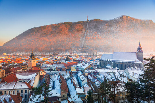 Brasov, Romania. Black Church and Carpathian Mountain, winter snowy downtown, sunset time.