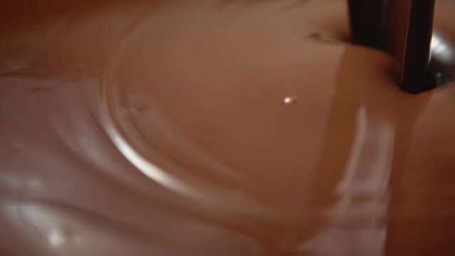 Close-up hot melted liquid chocolate flows, Pouring molten milk chocolate or brown caramel sauce. Cooking handmade chocolate dessert and candies. Confectionery manufacture