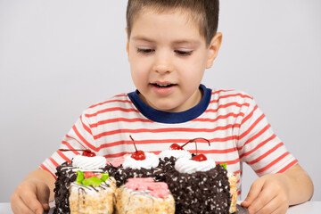 A happy 5 year old boy looks at a delicious cake and smiles on a white background