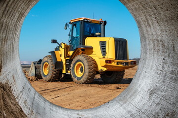 Bulldozer or loader moves the earth at the construction site against the blue sky. An earthmoving machine is leveling the site. Construction heavy equipment for earthworks.