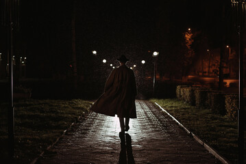 male detective in a hat and raincoat at night in a rainy city in the style of film noir