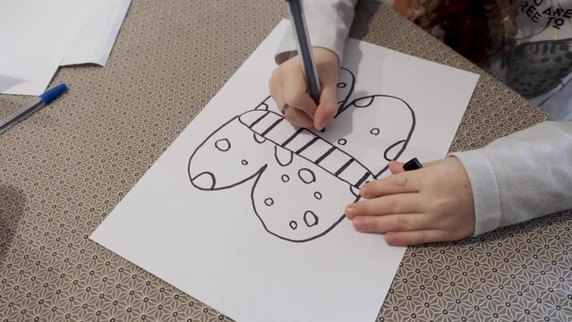 Kids art. Child with marker drawing a butterfly. Kids art. Little girl drawing a butterfly. Doodling with marker on paper. Free time. 4K