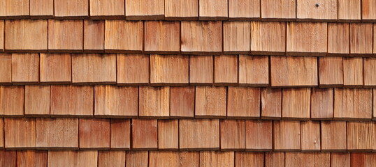 a house wall covered with small wooden tiles as a background 