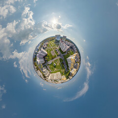 tiny planet in sky with clouds overlooking old town, urban development, historic buildings and...