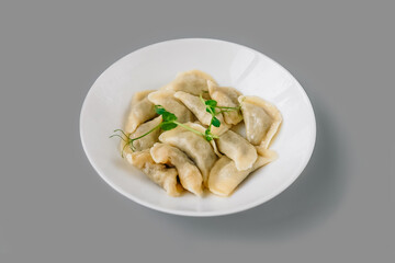 Boiled dumplings on white plate on gray.