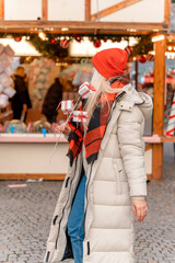 woman in orange scarf  walking in Christmas market decorated with holiday lights. Feeling happy in  city Christmas decorated.