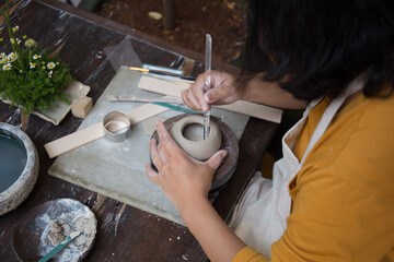 Fototapeta na wymiar Young Asian Female focusing on her job at the pottery workshop 