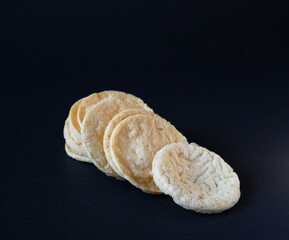 Puffed chips stack on black background with a chip leaning on stack, Healthy Snacks, Potato Puffed Chips, Its not baked not fried.