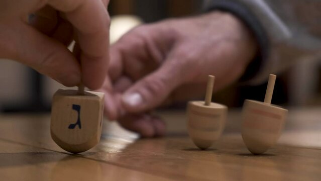 Jewish Dreidels spinning Close up. Hand spinning three Hannuka dreidels. Jewish holiday traditions. Playing in the holidays with toys sevivon