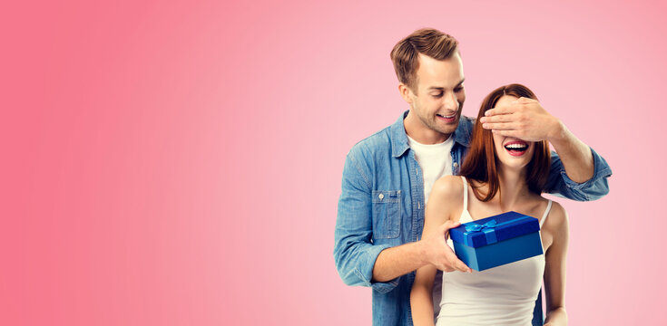 Holiday sales actions, rebates, discounts offers concept image - happy amorous couple with blue gift box. Isolated on vivid rose pink background. Copy space for some text.