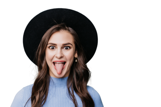 Playful brunette female hipster in hat with brim and lilac sweater shows tongue with wide opened eyes over transparent background. Crazy girl having fun, excited woman. Youth. Mockup, madness! - Powered by Adobe