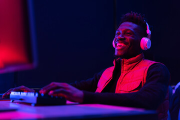 Young African man playing video game on computer. Streamer guy sitting at home and plays another match.