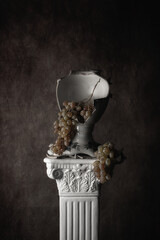 Photo still life with grapes and a broken vase on a column
