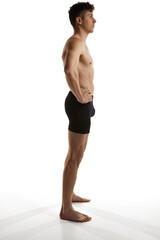 Obraz premium Side view photo of mature handsome man posing shirtless in black boxers over white studio background. Men's health and beauty