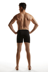 Rear view photo of mature handsome man posing shirtless in black boxers over white studio background. Strong back. Men's health and beauty