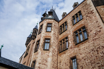 Wernigerode, Saxony-Anhalt, Germany, 29 October 2022:  Castle with tower in Harz mountains above town, Neo-Romantic style or historicism, Sculptures of griffins, dragon and eagles, sunny autumn day