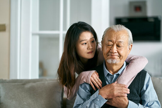 young asian adult daughter conforting senior father at home