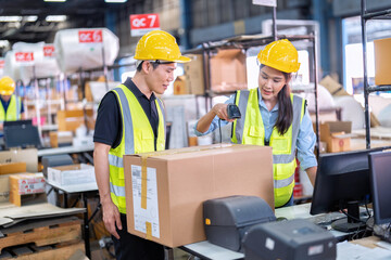 2 Staff working in large depot storage warehouse check packing box and scan at cashier counter