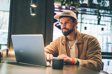 caucasian young man with lgbt bracelet working in laptop