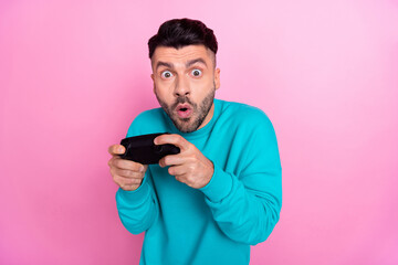 Photo of funny young nervous addicted gamer man wear blue jumper playstation gamepad crazy hard videogame moment isolated on pink color background © deagreez