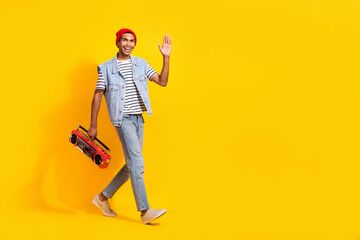 Full body profile portrait of positive person hold boombox arm palm waving hi walk empty space isolated on yellow color background