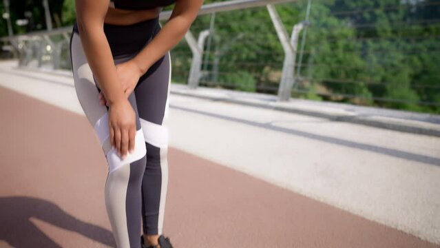 African American woman feeling pain in the knee while running, sports injury