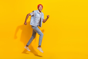 Fototapeta na wymiar Full length photo of funky excited man wear jeans outfit jumping high running empty space isolated yellow color background