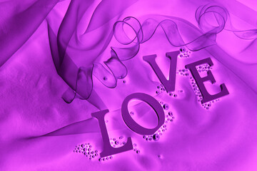 "LOVE"の文字と真珠とリボンとオーガンジーの背景（ピンク紫のイメージ）
