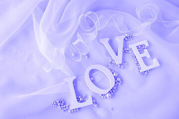 "LOVE"の文字と真珠とリボンとオーガンジーの背景（薄紫のイメージ）
